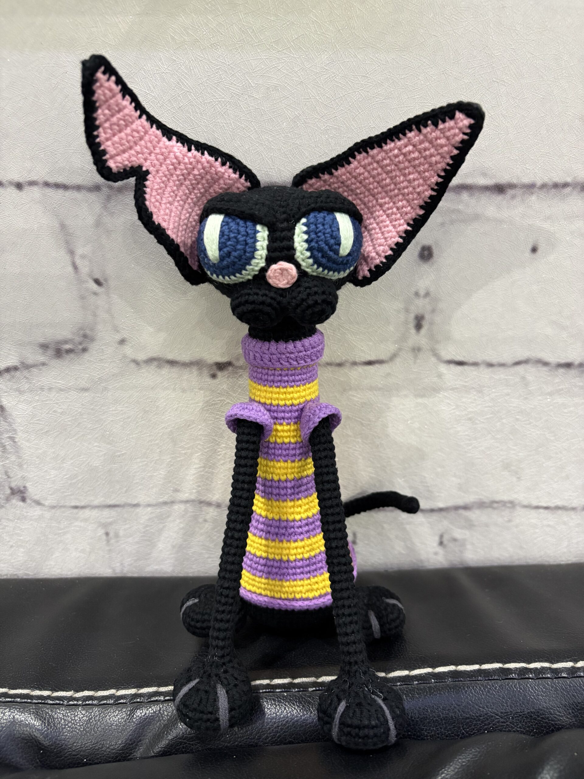 Handmade crochet black cat doll with pink ears and striped scarf